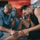 a man holding his knee in pain with a medical professional checking his knee with his hand